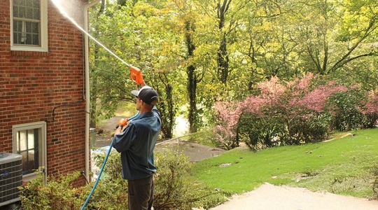 Man pressure washing house