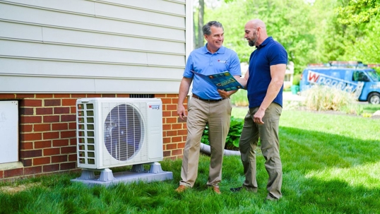 employee chatting with man in front of ac